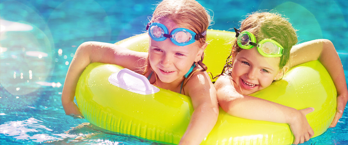 Zwei fröhliche Kinder mit Schwimmring im Wasser