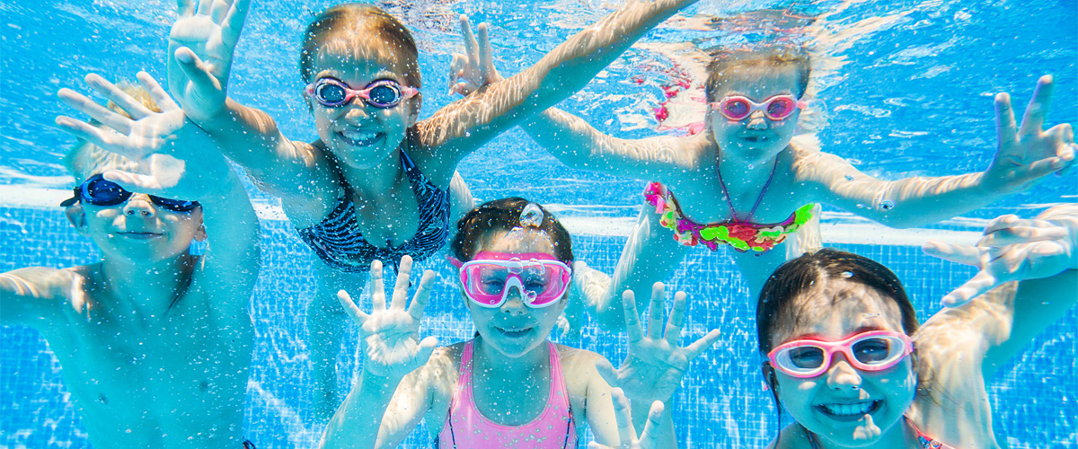 Fünf Kinder mit Schwimmbrillen tauchen fröhlich im Wasser